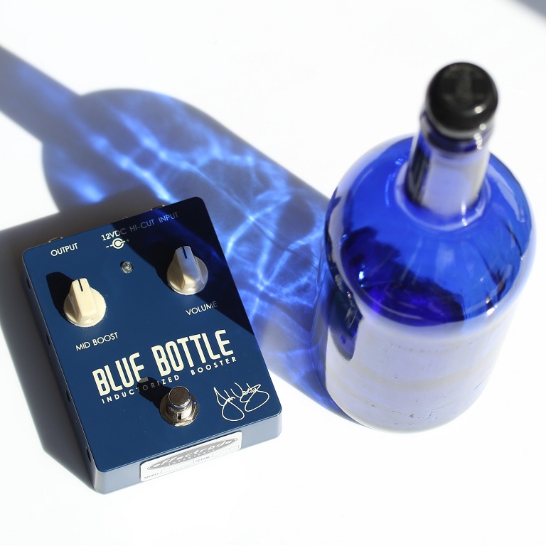 Booster Guitar pedal and a blue glass bottle